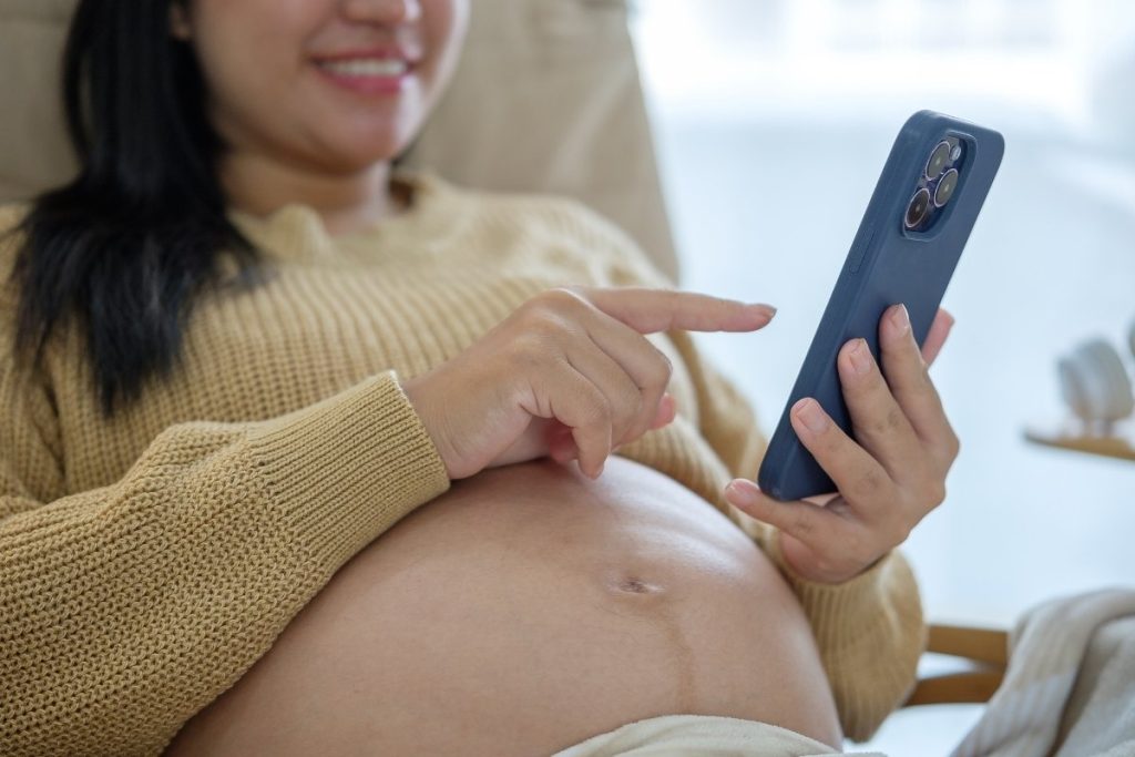 Mujer embarazada en Colombia comprando ropa infantil online desde su celular.