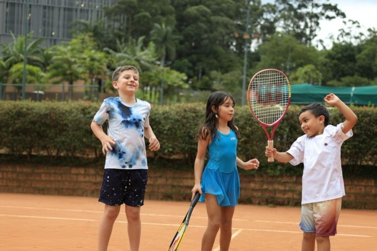 Niños jugando tenis con ropa deportiva transpirable; un niño con camiseta tie-dye y una niña con vestido azul