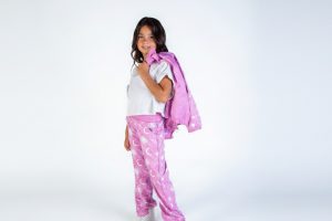 Niña posando con un conjunto de viaje rosa estampado con lunas y una chaqueta ligera