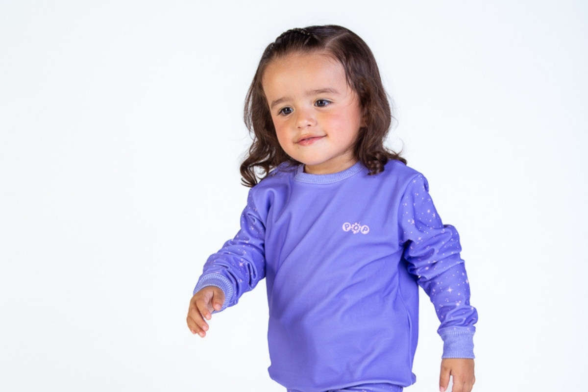 Niña pequeña caminando con una sudadera violeta de tela suave y elástica