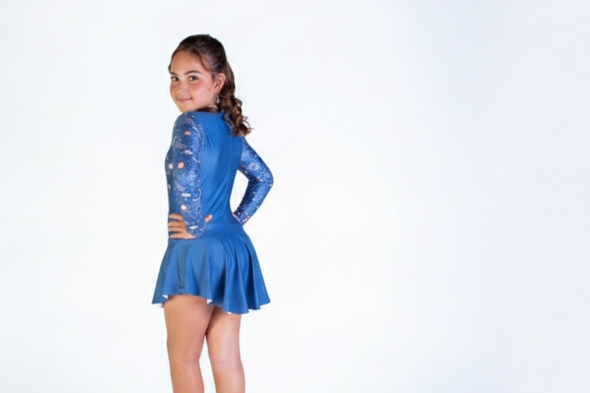 Primer plano de una niña luciendo un vestido deportivo azul de manga larga con estampado galáctico en las mangas.
